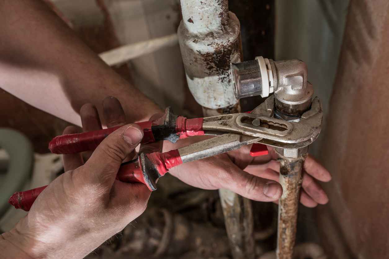 Plumber repairing old rusty pipes in house