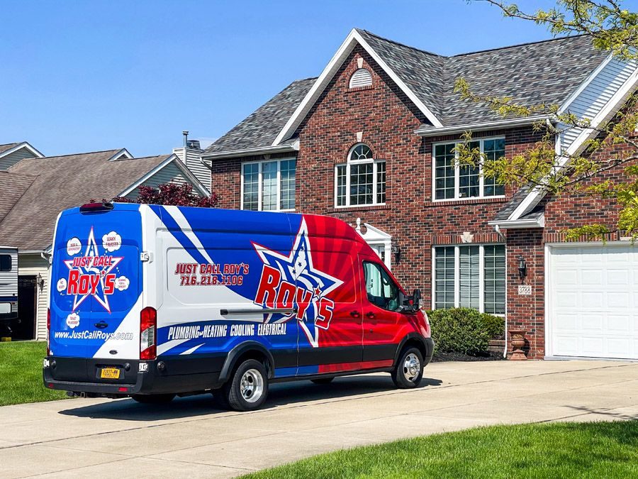 Roy's service van with red, white, and blue graphics parked in a suburban driveway beside a brick two-story house.