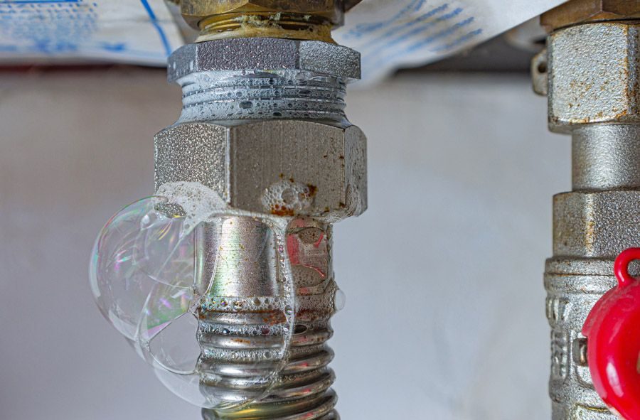 Broken incandescent light bulb attached to a metal pipe fitting; shattered glass and rust visible around the fixture