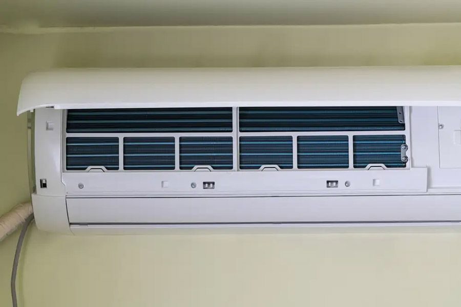 Wall-mounted split AC indoor unit with front panel lifted, exposing blue filter coils behind the grille.