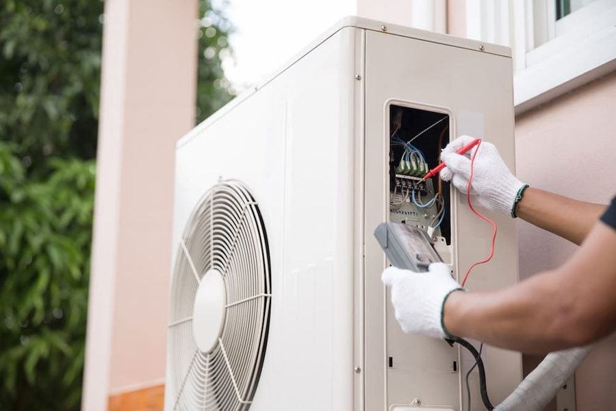 HVAC technician servicing a heat pump outside of a home